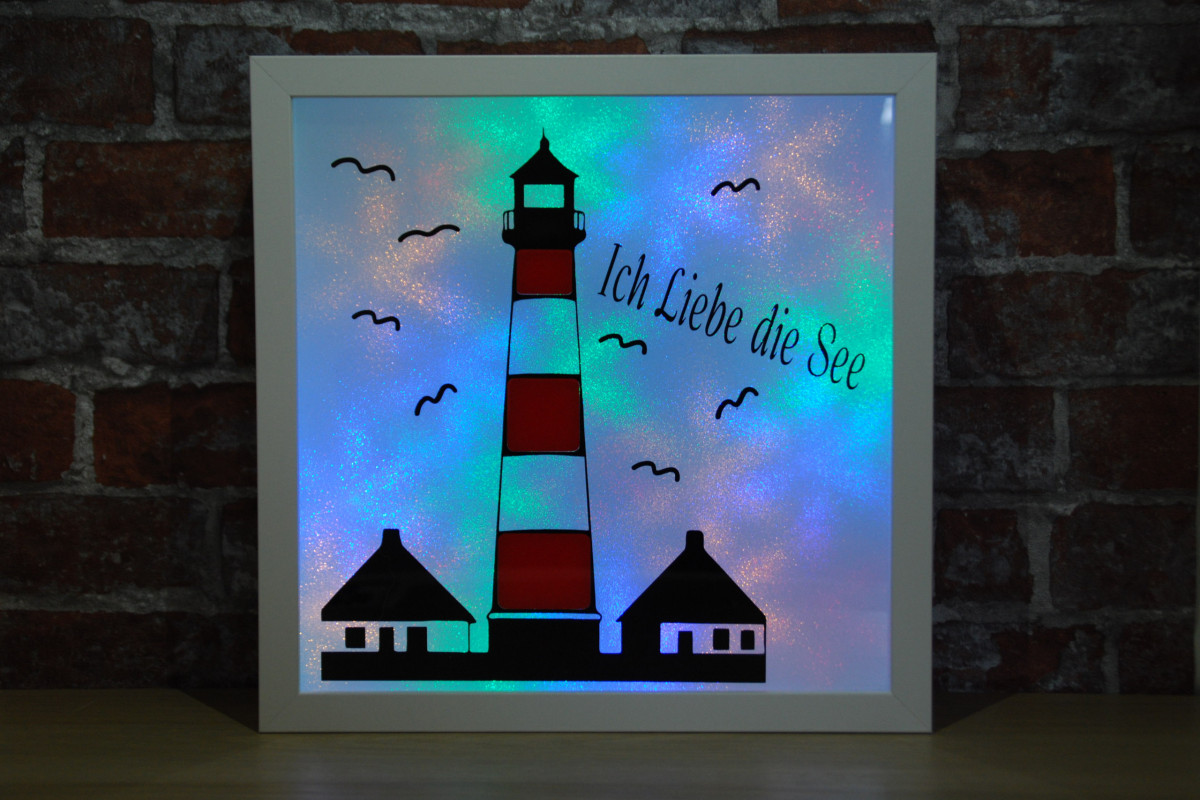 Beleuchteter Bilderrahmen mit Leuchtturm-Motiv, Glimmerfolie und farbigem Licht